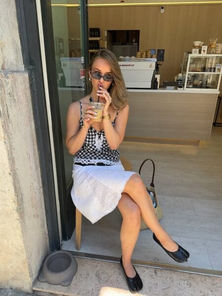 Woman in a black gingham lace cami and white eyelet midi skirt with black Tabi flats