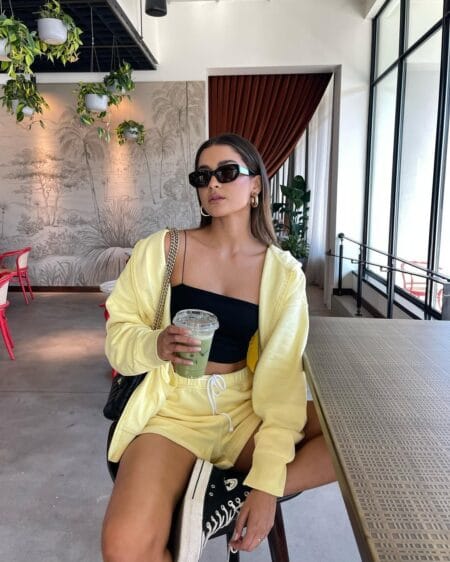 Woman in a buttercup yellow sweat set over a black bandeau crop with black high-top trainers