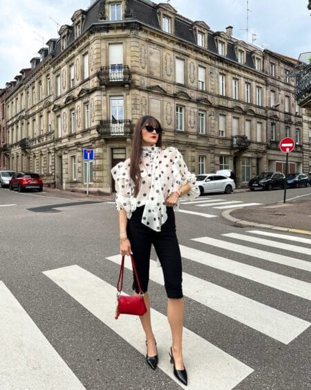 Sheer polka dot blouse with black capri pants and red handbag outfit