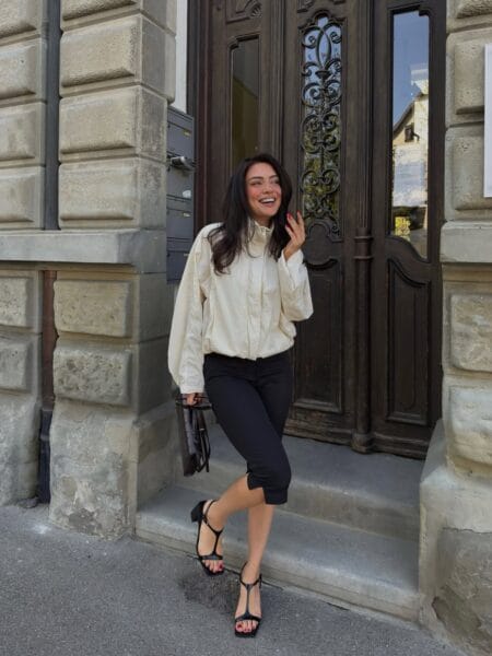 Cream windbreaker jacket with black capri pants and T-strap heels