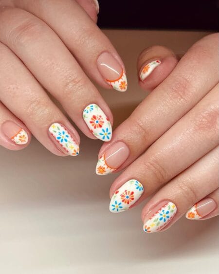 Short almond nails with white base covered in multicolour folk-art florals in orange, blue, red and yellow — Spanish tile nail art