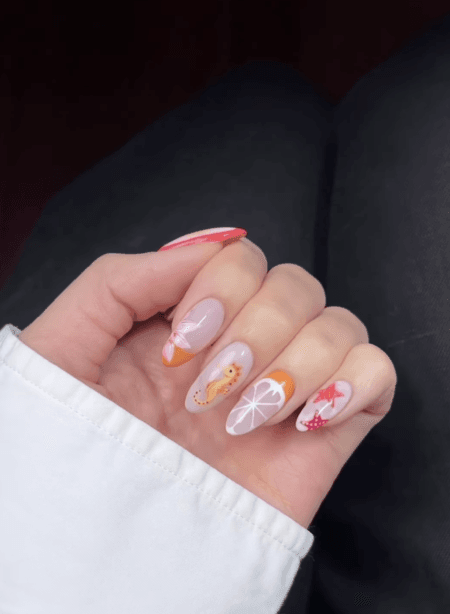 Almond nails with coral French tip, hibiscus motif, golden seahorse, citrus cross-section and pink starfish art