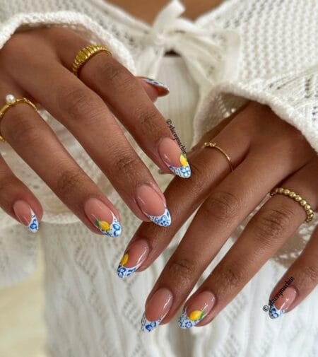 Long almond nails with wide white French tips painted in cobalt Sicilian tile patterns and yellow lemon corner detail