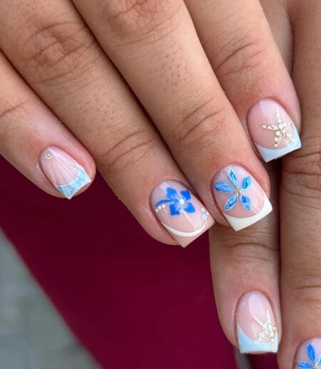 Short square nails with pale blue French tips, cobalt hibiscus, crystal starfish, scallop shell art and gold bead details