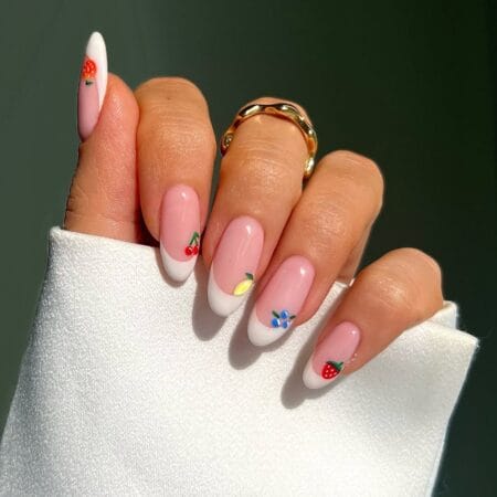 White French tip almond nails with hand-painted summer fruit motifs including cherries, strawberry, lemon and blueberries