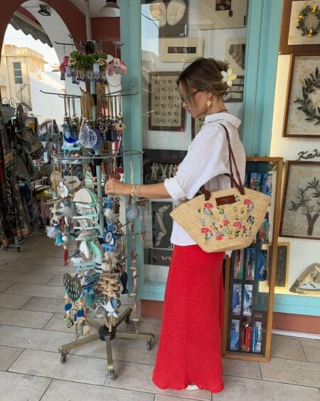 White linen shirt with red wide-leg trousers and floral straw tote July outfit