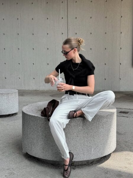 Black tee and white pinstripe wide-leg trousers with fishnet Mary Jane flats and cat-eye sunglasses — june outfits 2026