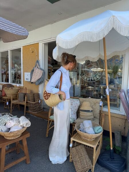 Blue stripe broderie anglaise shirt and cream wide-leg linen trousers with round straw shoulder bag — what to wear in June