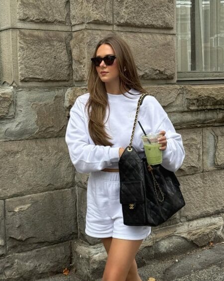 White Alo oversized crewneck sweatshirt and matching white shorts set with black quilted Chanel chain bag — summer casual outfits 2026