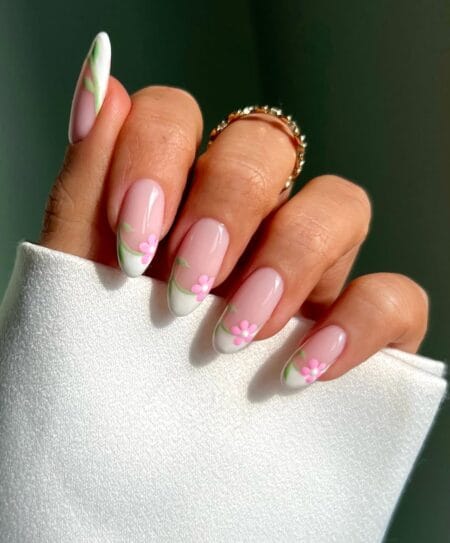 White French tip almond nails decorated with pink daisies and green vine accents.