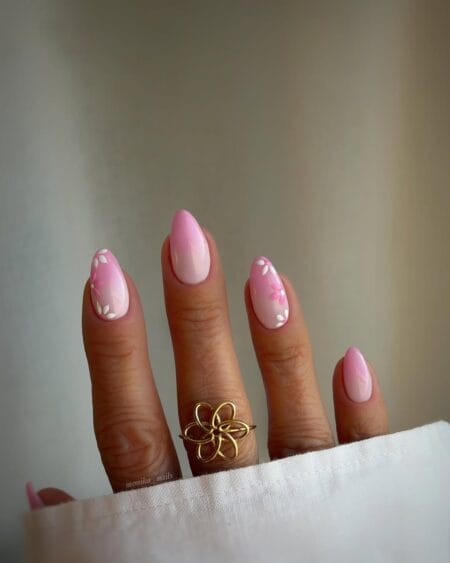 Pink ombré almond nails adorned with scattered floral petal details.