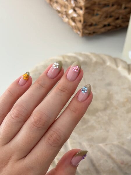 Khaki French tip almond nails decorated with colorful gem flower accents.