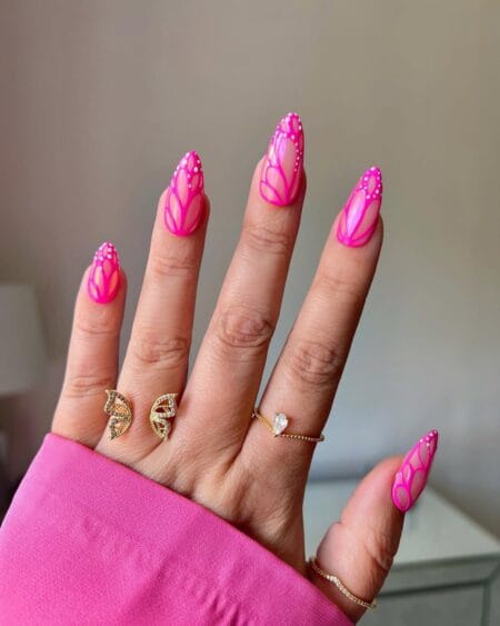 Neon pink almond nails featuring butterfly wing-inspired nail art.