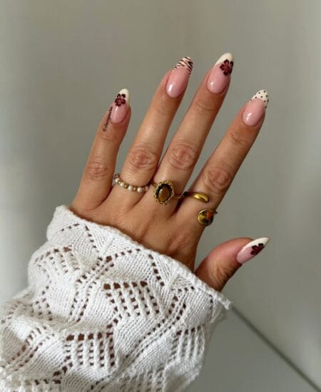 White French tip almond nails with burgundy hibiscus flowers and animal print accents.