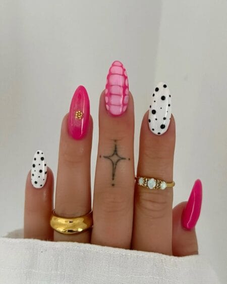 Hot pink almond nails with playful polka dot accents and mixed nail art designs.
