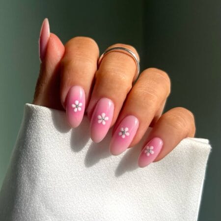Soft Pink Aura Nails With Daisy Charms — medium almond nails with blush to bubblegum pink aura gradient and white 3D daisy charms