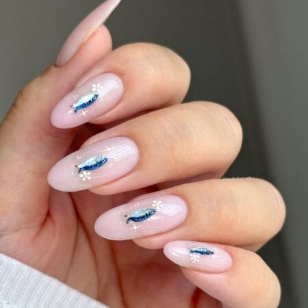 Sheer blush almond nails with hand-painted metallic blue sardine and white daisy accents — sardine nails for summer 2026