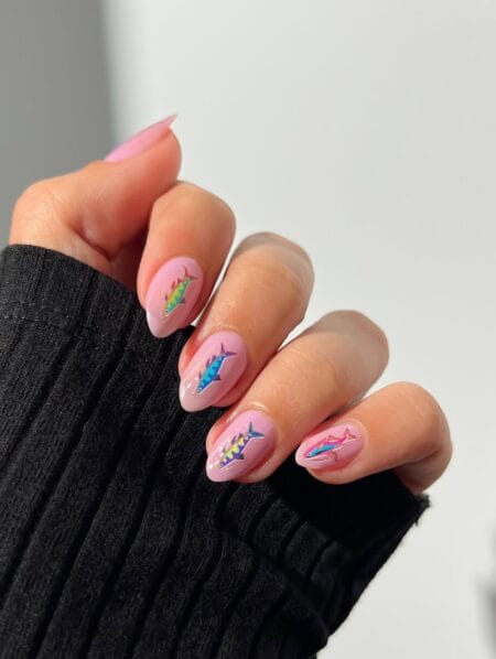 Baby pink almond nails with hand-painted fishing lure designs in green yellow, blue magenta and purple teal colourways — fish bait lure nails on pink almond 2026