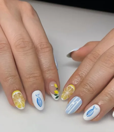 Short oval nails combining yellow lemon slice nail, sheer nude nail with blue sardine and lemon motifs, blue stripe nails — lemon and sardine coastal nails 2026