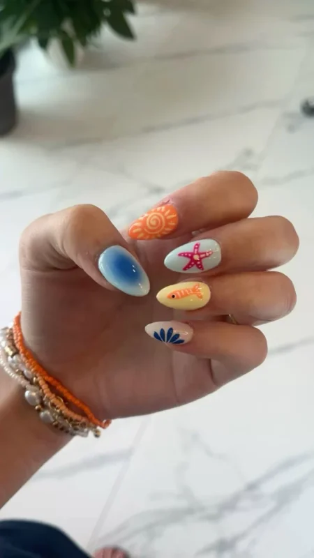 Medium almond nails combining orange sun nail, blue ombre nail, pink starfish nail, yellow fish nail and nude botanical fan nail — sun starfish and fish beach scene nails 2026