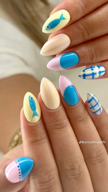 Long almond nails in butter yellow with blue sardine designs, pink yellow stripe nails, cerulean blue half-moon nail and blue gingham check nail — blue fish and gingham butter yellow nails 2026