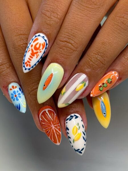 Long almond nails combining white crab tile nail, blue floral tile nail, ombre fish nail, beige lemon stripe nail, orange olive nail and yellow sardine nail — Mediterranean harbour maximalist fish nails 2026