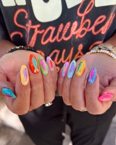 Rainbow almond nails each in a different solid colour carrying a matching hand-painted fish bait lure design — sardine bait lure nails summer 2026