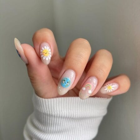 Smiley sun and rainbow whimsy july nail ideas on sheer milky almond nails with hand-painted characters