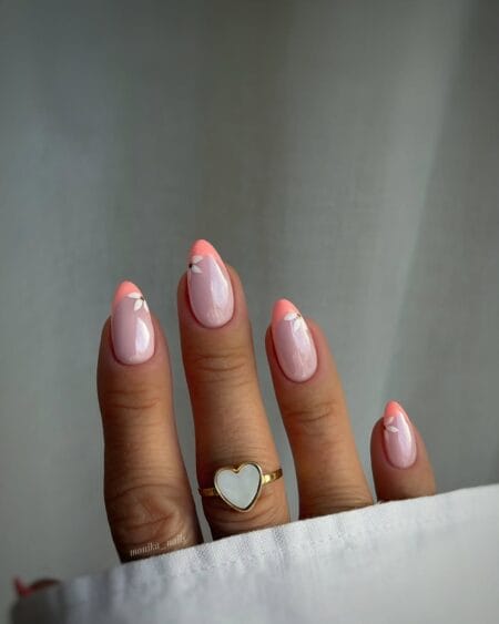 Coral French tip almond nails with iridescent base and white daisy detail july nail design