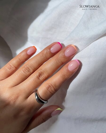 Rainbow neon micro French tip nails in orange fuchsia peach pink and lime on sheer nude base