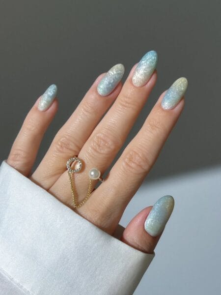 Opalescent sea glass texture nails in icy blue and white crinkled foil finish on almond shape