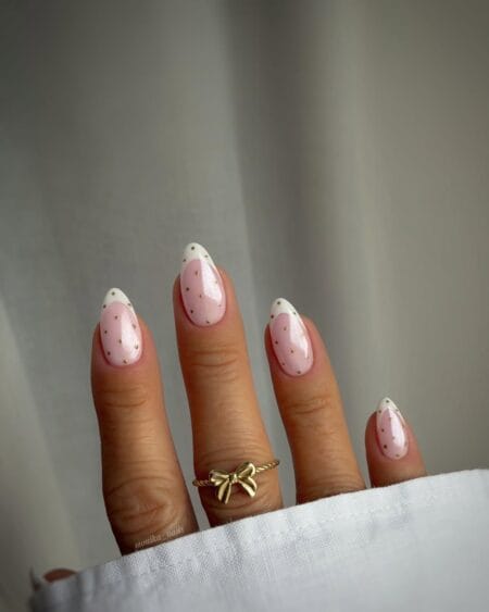 Blush and gold polka dot French tip nails with metallic micro dots on sheer pink almond nails