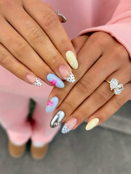 Mixed maximalist polka dot and chrome nail set with black dot French tips, silver stud accent and butter yellow base