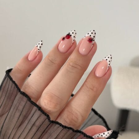 White polka dot French tip nails with black dots and red 3D ladybird charms on long almond nails