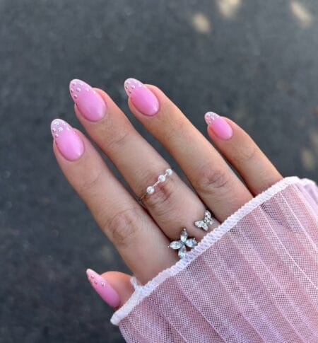 Hot pink polka dot nails with silver stud dots clustered at cuticle on glossy almond nails