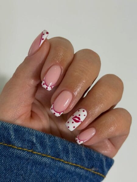 White French tip polka dot nails with magenta dots, curved border line and red lip accent on short square nails