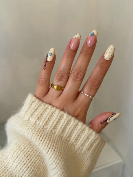 Cream French tip and blue forget-me-not polka dot nails with floral detail on long almond nails