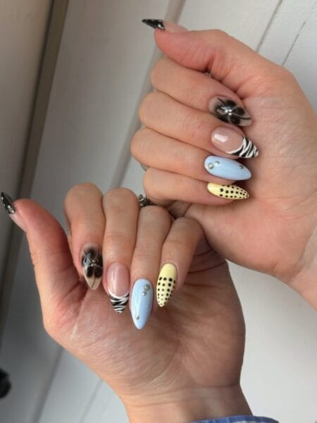 Zebra print and yellow polka dot mixed pattern nails with crystal dot accents and black floral detail on almond shape