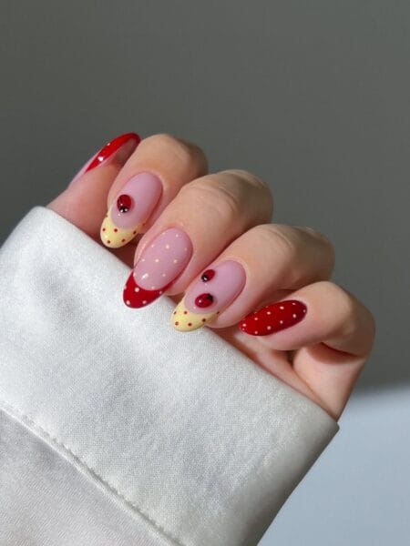Red polka dot nails with ladybird charms, butter yellow dot tips and mixed almond nail set