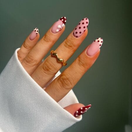 Berry and blush mixed motif polka dot nails with burgundy dots, floral accent and white dot French tip on almond nails