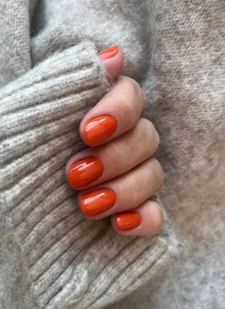 Burnt orange glossy nails in a warm pumpkin-inspired shade.