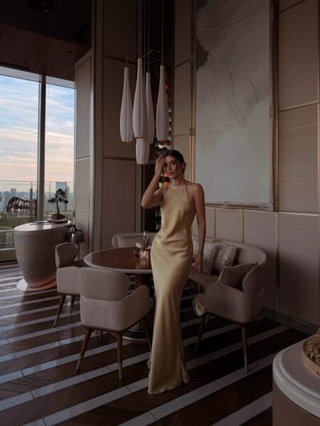 Butter yellow halterneck cowl gown with open back, autumn wedding guest dress