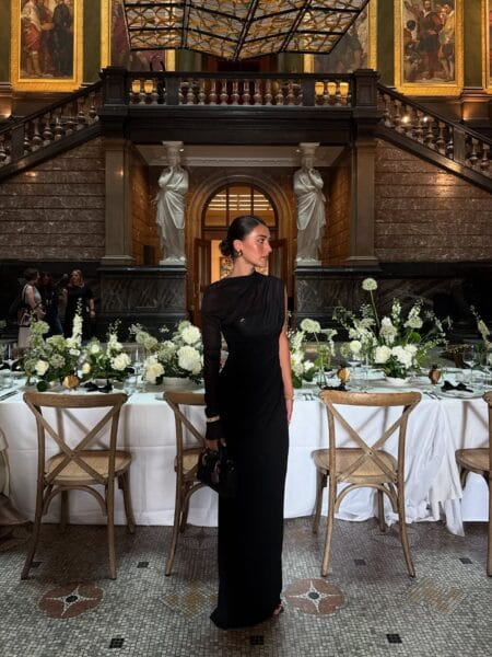 Black one-shoulder draped gown with sheer sleeve, fall wedding guest outfit
