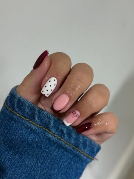 Maroon French nails with polka dot and bow accents