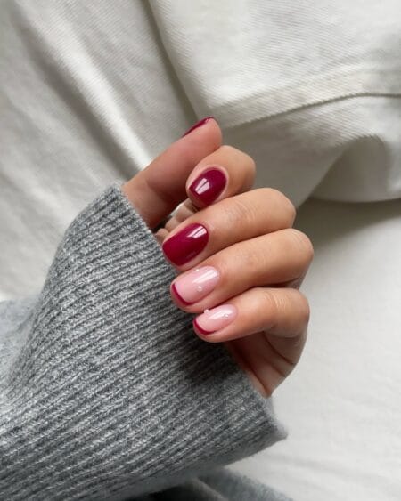 Berry red nails with nude French and pearl accents