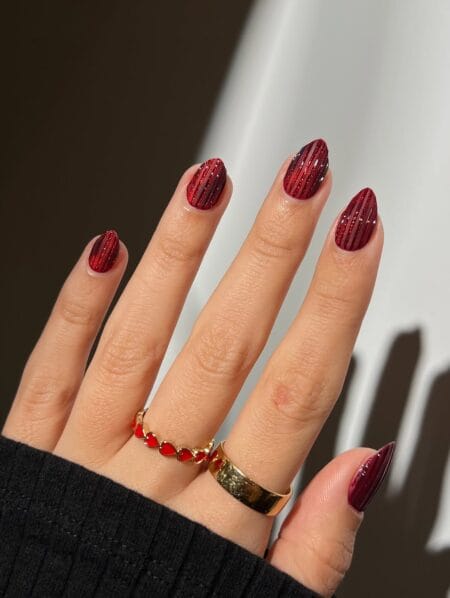 Glittered maroon stripe nails on almond shape