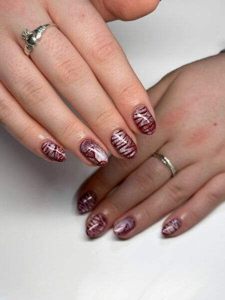 Shimmering maroon tiger stripe nails on short round nails