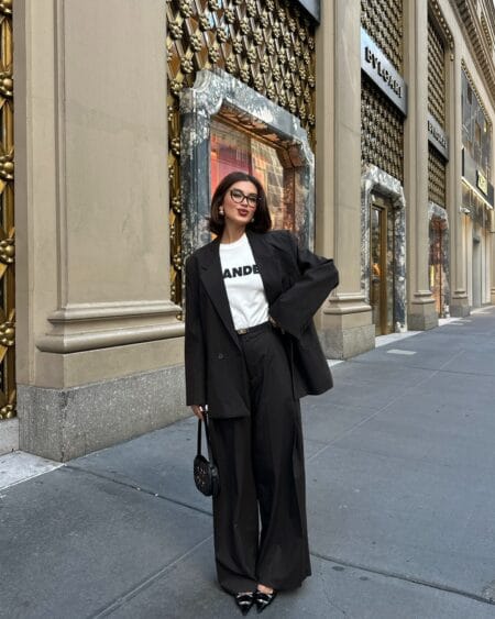 Woman in an oversized brown pinstripe suit with a white slogan tee and patent pointed heels