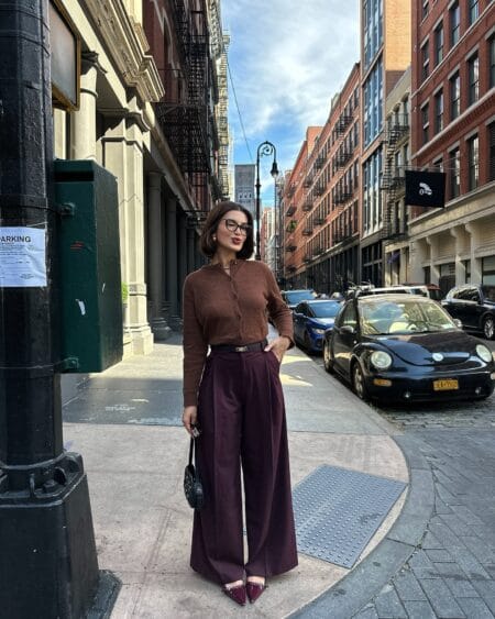 Woman in a rust brown mohair cardigan with aubergine wide-leg trousers and burgundy slingbacks in SoHo