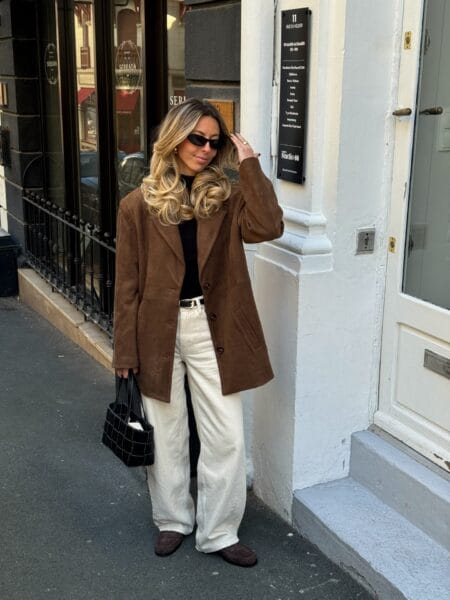 Woman in an oversized brown suede blazer with a black turtleneck and ecru wide-leg jeans